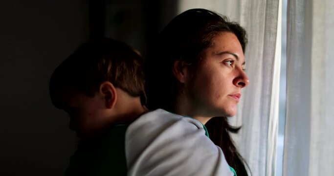 Mother holding toddler looking out window