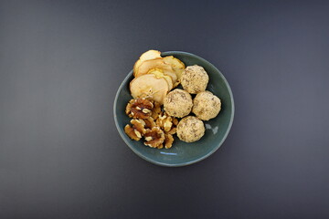 Energy balls from walnuts and dried apples in a round bowl on a gray background. A simple and healthy snack.