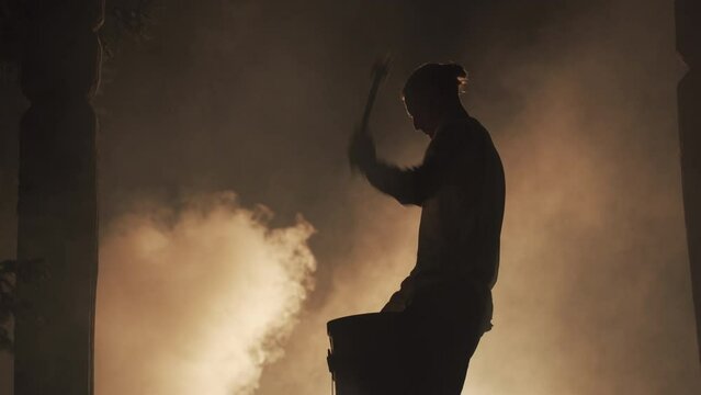 Man performing with drums at night with smoke background
