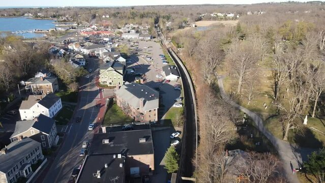 Drone pullback view of parking areas, harborside, roadways and commercial area of Hingham, MA USA. Revealing open areas, cemetery.