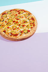 Italian pizza with chicken and pickled cucumber on coloured background. Cheese pizza with chicken in minimal style on purple and blue colours. American pizza delivery concept with color backdrop