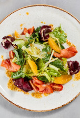 Healthy food - salmon salad with vegetables, greens and citrus. Summer salad with salmon, beetroot, orange and citrus dressing on concrete background. Summer menu in minimal style. Aesthetic food.