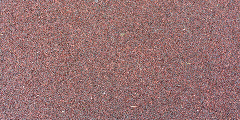 A texture of small pebbles bound with a plastic compound. Dark red color