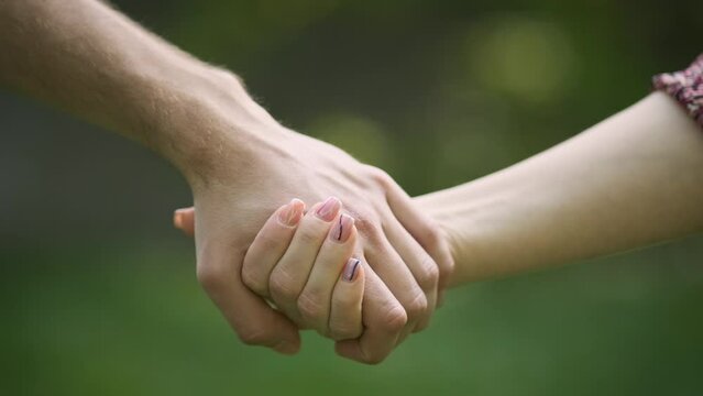Couple holding hands in the Park. Hold on, hands, couples. Couple hold hand in the autumn or summer park. Closeup of loving couples holding hands while walking. Female and male hand together