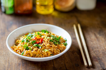 or breakfast before going to work, stir fried noodles in a white plate on a wooden table.