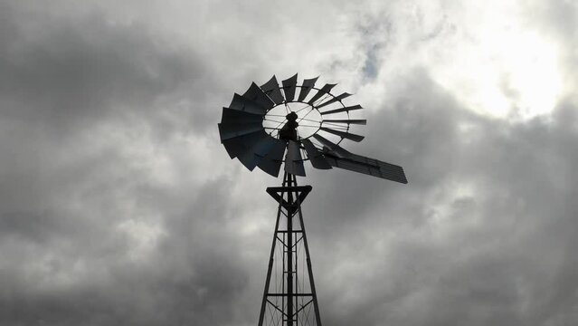Looking up at a spooky old fashioned windmill on a cloudy day