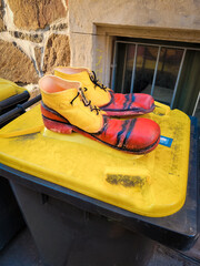 Funny clown shoes on the yellow garbage can