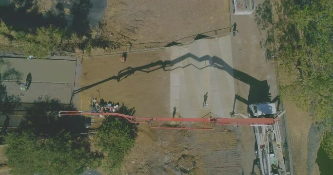 large concrete pumper pouring cement, drone shot, cement slab construction, cement mixer truck, cement ramp construction on lot, aerial video over residential