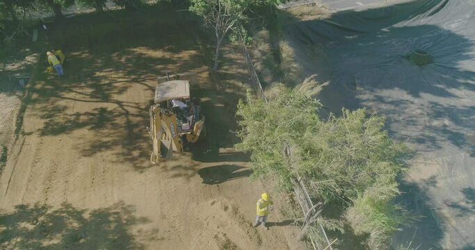 Excavators settling earth and construction workers, drone shot, cement slab construction, cement mixer truck, cement ramp construction on lot, aerial video over residential