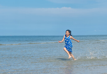 Asian little girl is running on the beach