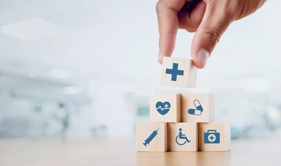 Close up man hand arranging wood block with healthcare medical icon on hospital background. Health...