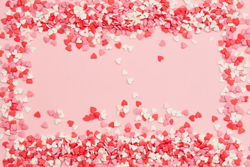 Candies hearts of pastel colors on pink paper. Top view. Valentine's Day background. Valentine day greeting card or banner. 