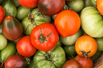 Colorful green orange red tomatoes close-up, top view background texture