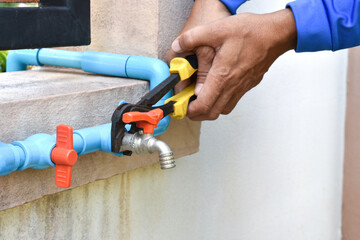 Technician man hand using pvc pipe cutter for cut the water pipe at home. Maintenance concept.