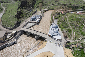 Ancient stone bridge across Kars River & Kars Castle - main tourist attractions of Kars, Turkey. Near flag (on castle) are portrait of Ataturk & writing in Turkish 'Motherland remembers you'