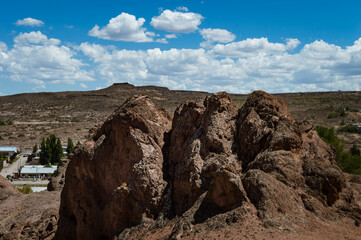 Basaltic rock formations in the desert area of Argentine Patagonia with the city of PIedra del Aguila in the background