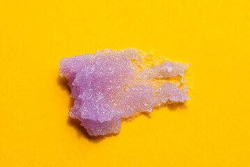 Purple sugar body scrub texture on yellow background. Cosmetic smear. Appearance of the texture of the lilac swatch. Natural skincare products. Beauty concept for face and body care