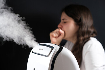 Humidifier and coughing woman in the background. Humidification of the air with cough and viral infections - obrazy, fototapety, plakaty