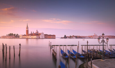 Venice lagoon at sunrise, San Giorgio Maggiore church and gondolas. Italy, Europe. Long exposure photography.