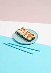 Baked Maki roll with shrimp and cheese on ceramic plate. Hot sushi roll with cheese topped on coloured background. Japanese menu concept. Hot sushi roll in modern style.