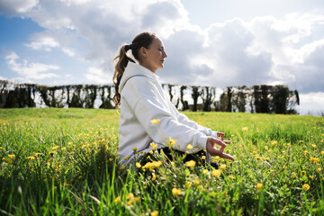 Calm smiling woman meditating at the grass