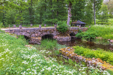 Old stone bridge over a river with wildflowers