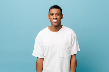 Portrait of cheerful young african-american guy wearing white casual t-shirt posing isolated on...