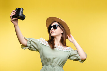 Pretty girl in hat and summer dress taking selfie on camera.