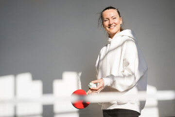 Cheerful woman holding tennis racket while playing at the ping pong at home