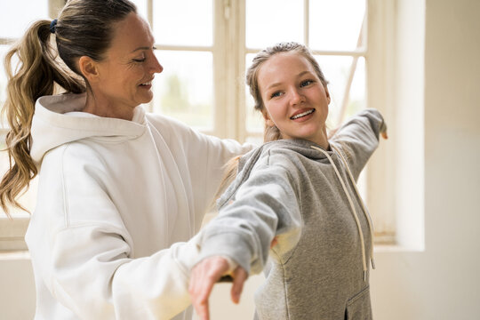 Mother helping to her daughter making right posture during the sport at home