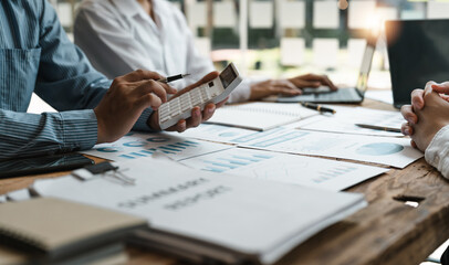 Accountant or bookkeeper working with calculator to calculate business data summary report,...