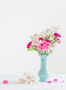 pink and white flowers in blue vase on white background