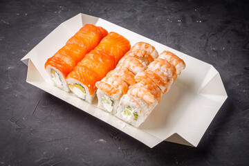 delicious sushi rolls in a delivery box on a black background