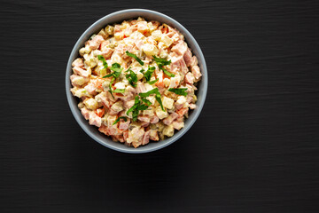Homemade Olivier salad in a Bowl on a black wooden surface, top view. Flat lay, overhead, from...
