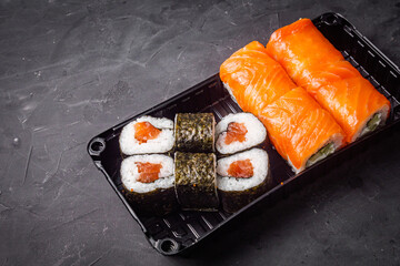 delicious sushi rolls in a delivery box on a black background