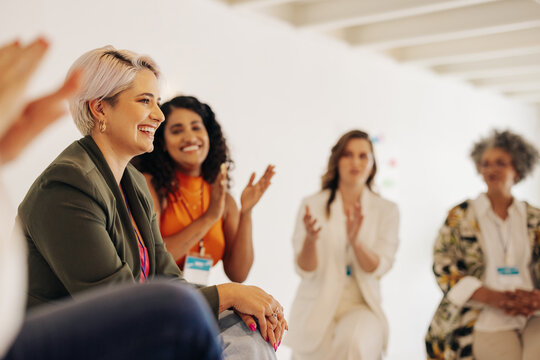 Smiling businesswomen applauding their colleague in an office