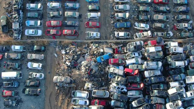 Looking straight down on thousands of smashed cars, trucks, SUVs reduced to scrap metal, spare parts, in junkyard, aerial view.