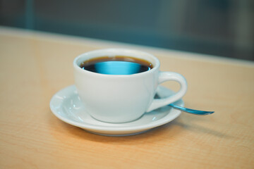 Coffee cup close up shot in a bar against a window on a wooden counter
