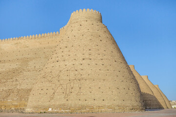 Fototapeta na wymiar Massive walls of the Ark fortress in Bukhara, Uzbekistan. Citadel is the oldest building in the city. Legends attribute the foundation of the fortress to the legendary hero Siyavush