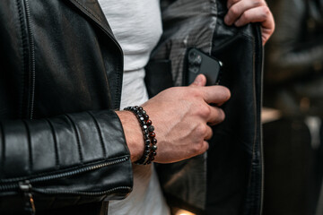 Bracelets made of artificial stones, on a man's hand. Business style, smartphone in pocket.