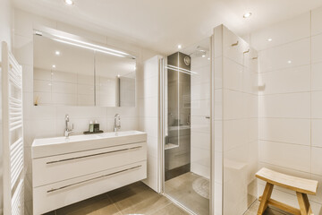 Light bathroom with white tiled walls and shower cabin near cabinet