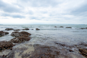 Fototapeta na wymiar Ocean waves crashing against rocks on the sandy beach