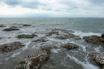 Fototapeta na wymiar Ocean waves crashing against rocks on the sandy beach