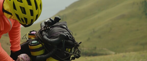 The stylish woman travels on a bicycle with bikepacking bags. The sportswoman traveler journey on...