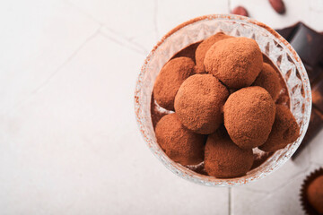 Chocolate truffles. Homemade chocolate truffles with cocoa powder on glass on old cracked tile table background. Tasty sweet chocolate truffles candies. Valentine's Day and Mother's Day concept.