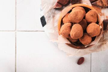 Chocolate truffles with cocoa powder in wooden dish on old cracked tile table background. Tasty sweet chocolate truffles candies. Valentine's Day and Mother's Day concept with copy space. Top view.
