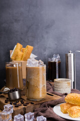Fototapeta na wymiar Asian iced coffee in transparent glass and roasted coffee beans and Crispy Pie on wood. black background studio photo, Copy space for your text