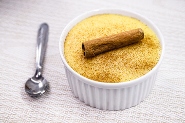 Bowl with corn jam called Curau, jimbelê or hominy, decorated with cinnamon bark in cinnamon powder, copyspace