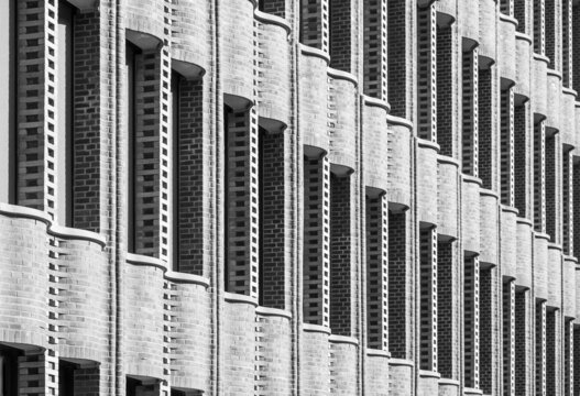 Geometric abstraction of repeating elements of the brickwork of the facade of the building with undulating ledges. Black and white photo