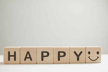 HAPPY word and smile face icon on wooden cube over white background with copyspace.